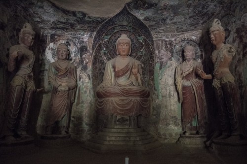 In a Mogao cave, lit by the flashlight of a guide, a Buddha statue surrounded by disciples dating from the Tang Dynasty. Dunhuang grotto art is a combination of architecture, painted sculpture and murals. (Gilles Sabrié/For The Washington Post) 